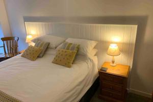 um quarto com uma cama branca e um candeeiro numa mesa de cabeceira em Bojewyan Cottage, Sandy Beaches and Great walking em Penzance