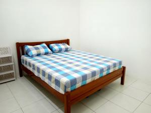 uma cama com lençóis e almofadas azuis e brancos em xadrez em Homestay Idaman 2 em Bukit Kayu Hitam