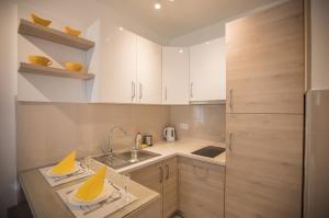 Una pequeña cocina con gabinetes blancos y un fregadero. en Jelena Apartment II, en Doboj