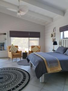 a bedroom with a bed and chairs and a window at Albatross Guesthouse in Langebaan