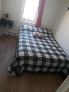 a bed in a room with a checkered blanket at Gestion clin d'oeil - 503 in La Tuque