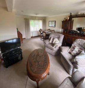 uma sala de estar com sofás, uma televisão e uma mesa em Dallaire House em Banchory