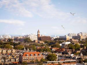 Eine Stadt mit Gebäuden und Vögeln, die in den Himmel fliegen in der Unterkunft Novotel The Hague World Forum in Den Haag