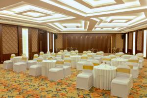 a room with white tables and chairs in a hall at Jenneys Residency in Coimbatore
