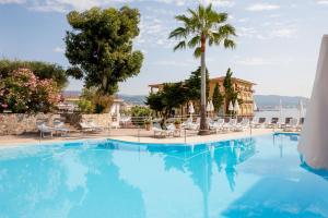 een groot zwembad met stoelen en een palmboom bij Hotel Moresco in Diano Marina
