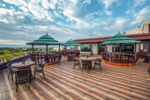 a deck with tables and chairs and umbrellas at Jenneys Residency in Coimbatore