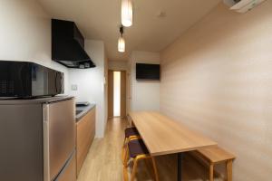 małą kuchnię z drewnianym stołem i lodówką w obiekcie Connect inn Kujo-Kawaramachi w mieście Kioto