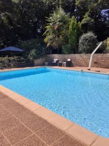 une grande piscine bleue avec un mur en briques dans l'établissement Gîtes du Bois de Bontemps, à Sarlat-la-Canéda