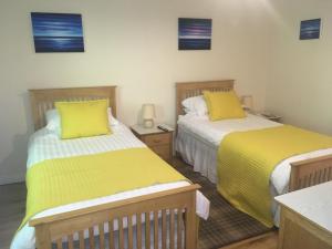 two beds in a room with yellow sheets at Stonewater House Vegan Bed and Breakfast in Lamlash