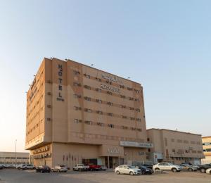 een groot gebouw met auto's geparkeerd op een parkeerplaats bij Al Masem Luxury Hotel Suites 3 Al Ahsa in Al Hofuf