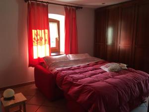 a bedroom with a bed with red curtains and a window at Lo PONTON in Introd