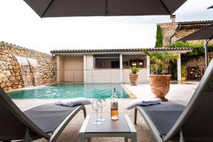 a bottle of wine sitting on two chairs next to a swimming pool at Le Trésor des Templiers in Malataverne