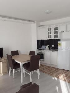 a kitchen with a table and chairs and white cabinets at Perla Del Mar Aparthotel in Lozenets