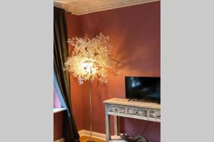 a room with a table with a television and a chandelier at Perfekter Altbaucharme in zentraler Lage ! in Kiel