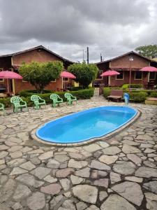 - une piscine avec des chaises, une table et des parasols dans l'établissement Chalé Brisa de Gravatá, à Gravatá