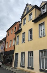 un edificio giallo con finestre bianche su una strada di Apartment am Schloßplatz Erlangen a Erlangen