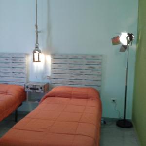 1 dormitorio con 2 camas de color naranja y lámpara en Granada Old Town Hostel, en Granada