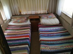 2 camas en una habitación pequeña con mantas coloridas en Őrségi Nomád-Lak Nomád 2, en Kercaszomor
