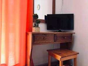 een televisie op een houten tafel met een kruk bij Pension Zoi in Kolimbia