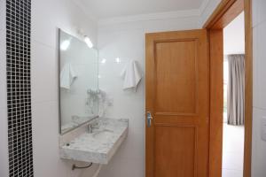 a bathroom with a sink and a mirror at Pousada Praia Do Meio in Torres