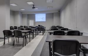 an empty room with tables and chairs and a screen at Hotel Grępielnia in Bielsko-Biala