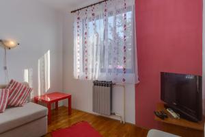 uma sala de estar com uma televisão e uma janela em House Ruzica em Mali Lošinj