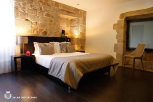 a bedroom with a large bed with a stone wall at Solar Dos Cáceres in Fornos de Algodres