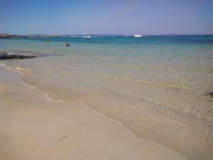 a beach with people swimming in the water at Apartamentos Las Dunas de Levante in Es Pujols