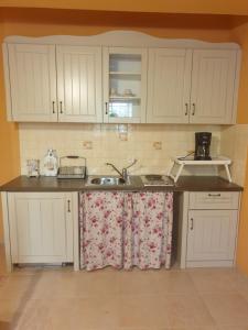 a kitchen with white cabinets and a sink at Traditional Guesthouse Marousio in Rodavgi