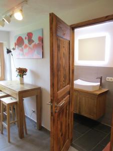 a bathroom with a wooden door and a desk and a tub at Ferienwohnung Rösch in Feuchtwangen