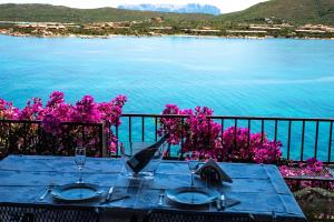 a table with two glasses and a view of the water at Casa Valery Wonderful Sea View in Porto Rotondo
