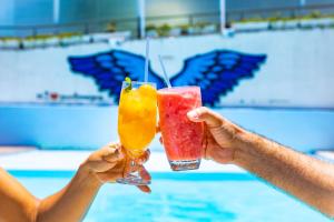 two people holding drinks in their hands near a swimming pool at H Ponta Negra Beach in Natal