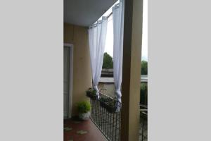 a balcony with white curtains and a window at T Rooms - Appartamento Dafne in Casale Monferrato