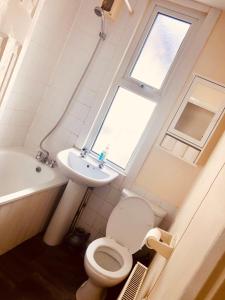 a bathroom with a toilet and a sink and a window at AC Lounge 125 in Rochford