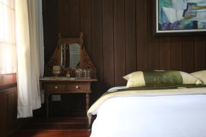 a bedroom with a bed and a mirror on a table at Villa Darakorn Hill Country House in Chiang Rai