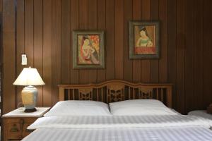 a bedroom with a bed and two pictures on the wall at Villa Darakorn Hill Country House in Chiang Rai
