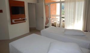 um quarto com 2 camas brancas e uma televisão em Flats termais em condomínio Apart Hotel de águas termais em Gravatal