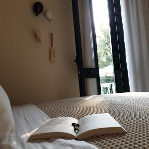 un libro aperto su un letto con finestra di B&B Il giardino ritrovato a Monteroni di Lecce