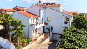 a white house with a palm tree in front of it at Apartments Vila Marinela in Poreč