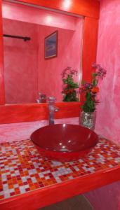 a red bathroom with a red sink with flowers at Sunset Hill Lodge in Bora Bora