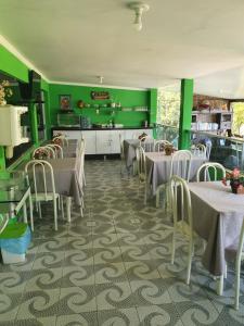 a restaurant with green walls and tables and chairs at POUSADA LIRIO DO VALE in Piranhas