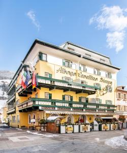 un edificio giallo con cartelli sul lato di Hotel Cavallino Bianco - Weisses Roessl a San Candido