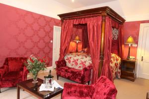 a red bedroom with a bed and a table and chairs at Mansion House Hotel in Elgin
