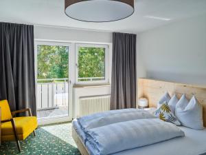 a bedroom with a large bed and a yellow chair at Apartments & Zimmer - Zugspitze in Leutasch