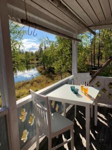 a white table and chair on a porch with a view of a lake at Forest Cabin in Swedish Lapland - A Retreat to Silence and Nature in Nattavaara