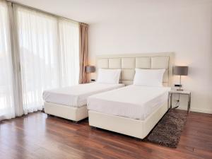 2 Betten in einem Schlafzimmer mit weißen Wänden und Holzböden in der Unterkunft B&B Demar Residence & Dependance in Zadar