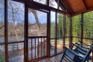 a screened in porch with a view of a river at Riverbend Lodging in Bryson City