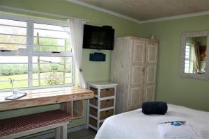 a bedroom with a bed and a desk and a window at High Palms (HPK) Guesthouse & kite school in Langebaan