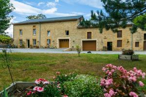 a large brick building with a yard with flowers at Le Moulin d'Harcy in Lonny