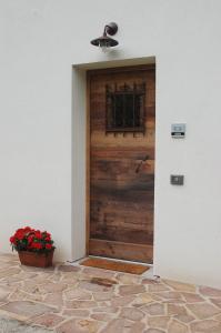 una puerta de madera con una ventana y una maceta de flores rojas en B&B Il Crogiolo en Bosentino